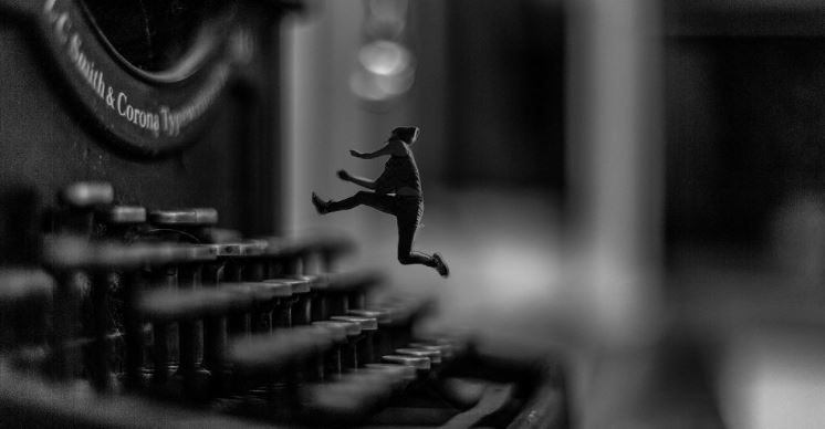 Composing: a tiny man running on the keys of a vintage typewriter